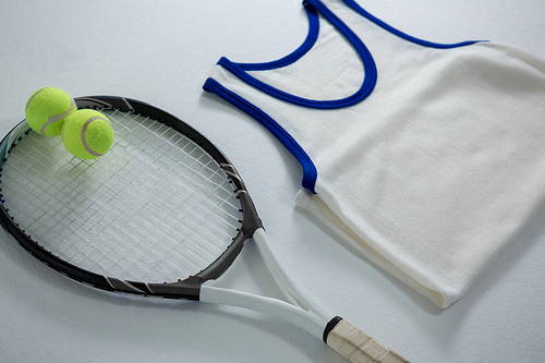 High angle view of racket with tennis balls by vest on white background