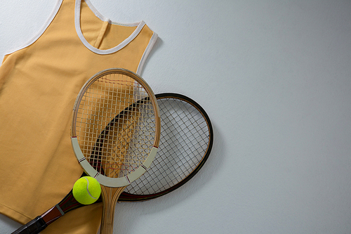 Directly above shot of rackets with vest and tennis ball on white background