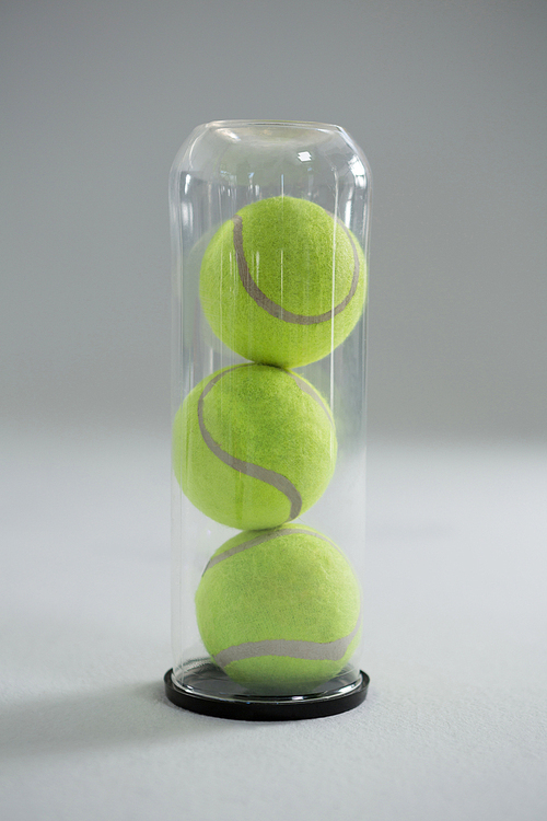 Close up of tennis ball in plastic bottle on white background