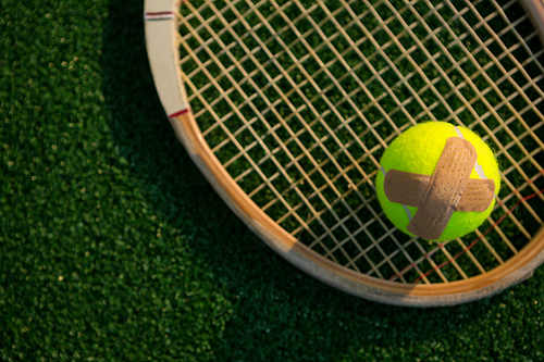 Overhead view of tennis ball with bandage on racket at field