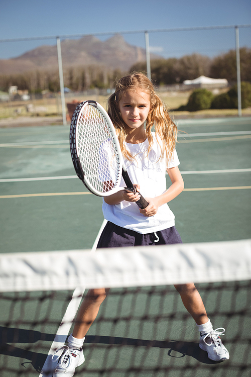 Portrait of girl playing tennis on court during sunny day