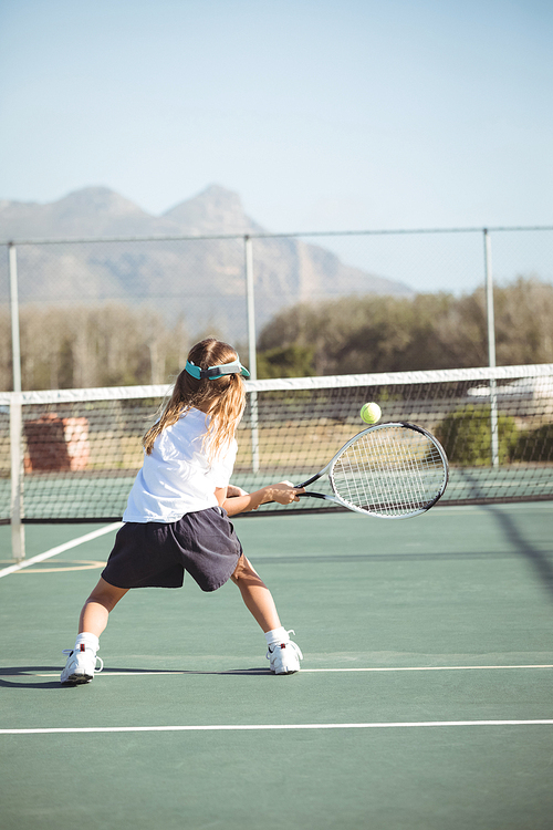 Rear view full length of girl playing tennis on court during sunny day