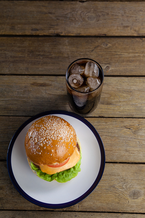 Overhead of hamburger in plate with glass of cold drink