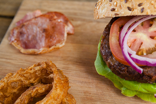 Close-up of hamburger and onion ring on chopping board