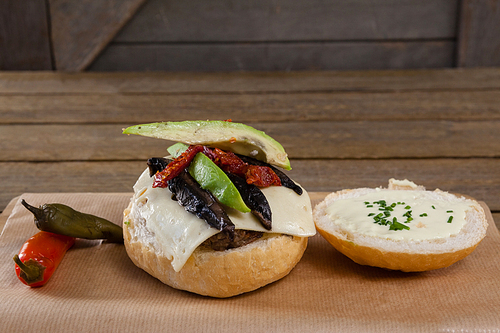 Close-up of chili peppers and burger on chopping board