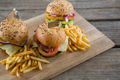 High angle view of burgers with lables by french fries served on cutting board