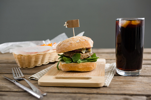 Hamburger with french fries and drink served at table against wall