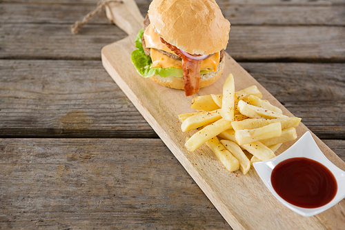 French fries with burger and sauce on cutting board