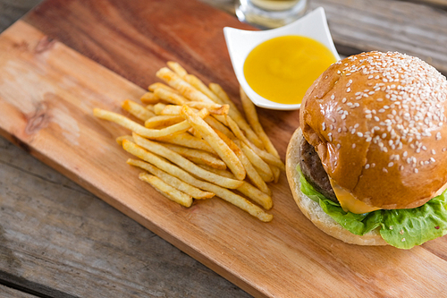 High angle view of hamburger with fries and dip on cutting board