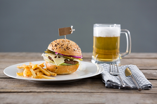 Close up of High angle view of hmburger with fries served in plate by beer glass on table