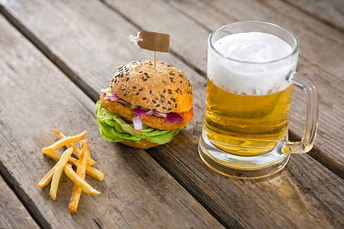 Close up of fries with hamburger and beer glass on table