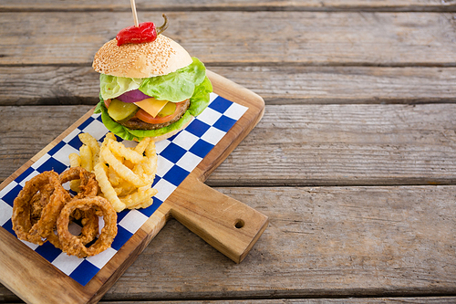 High angle view of onion rings and french fries with burger on cutting board