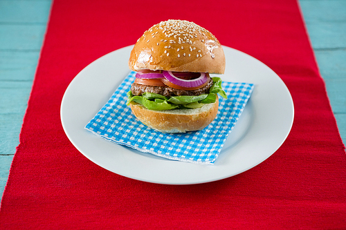 Close up of hamburger served on napkin in plate at table