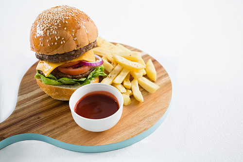 High angle view of hamburger with french fries and sauce on cutting board against white background