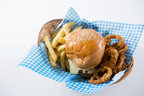 High angle view burger and French fries with onion rings in wicker basket