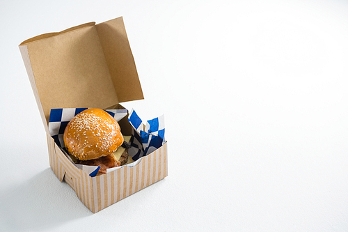 High angle view of cheeseburger in box on white table