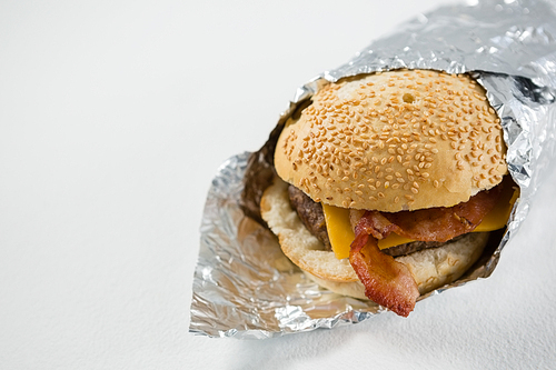 Close up of burger wrapped in foil paper on table