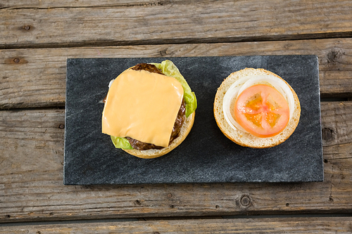 Overhead view of burger ingredients on slate at wooden table