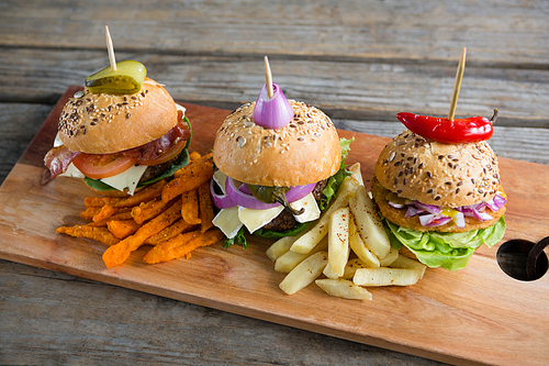 High angle view of various burgers on cutting board at table against wall