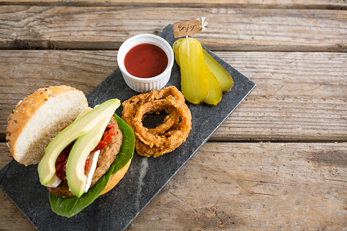 High angle veiw onion rings with burger on slate at table