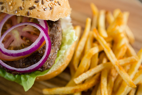 Close up of onion in burger by French fries