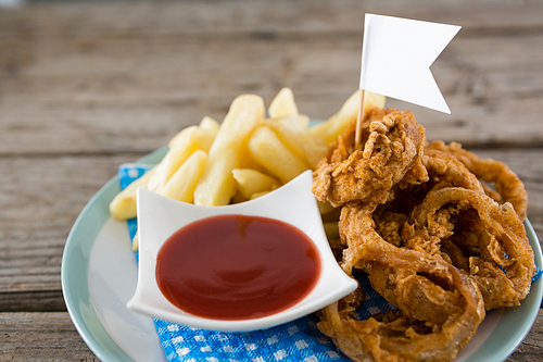 Onion rings with French fries served in plate on table