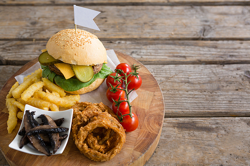 High angle view of vegetables with fried food by burger on cutting board