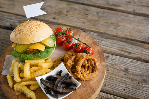 High angle view of ingredients with burger on cutting board at wooden table