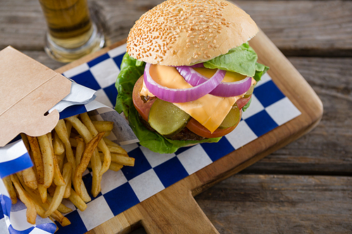 High angle view cheeseburger served with french fries and beer on cuttingbiard