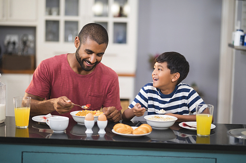 Happy young man with his son having breakfast in kitchen at home