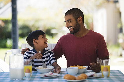 Happy young man with his son having breakfast at table