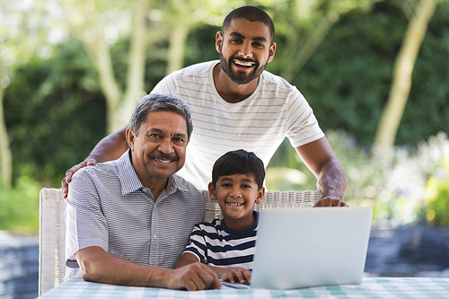 Portrait of happy multi-generation family using laptop together on table at porch