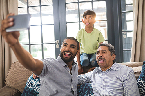 Happy multi-generation family making face while taking selfie together at home