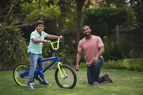 Portrait of father and son with bicycle at park