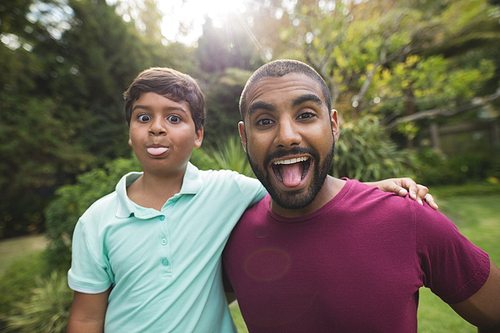 Portrait of mischievous father and son enjoying at park