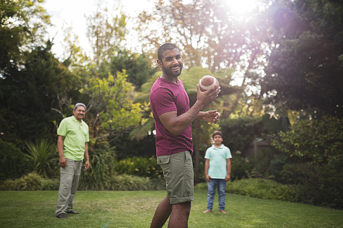 Portrait of man playing rugby with family at park