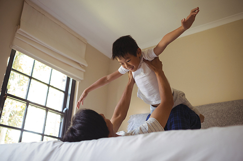Father playing with his son in bedroom at home
