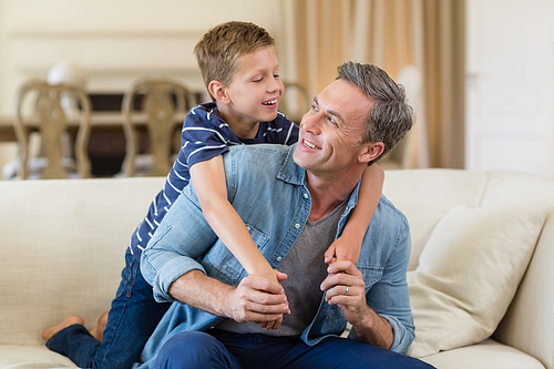 Smiling son embracing a father in living room at home