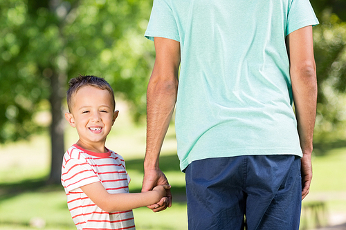Son holding hands of his father in park on a sunny day