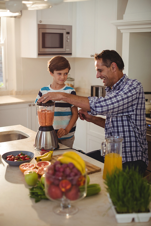 Father and son preparing smoothie in kitchen at home