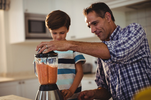 Father and son preparing smoothie in kitchen at home