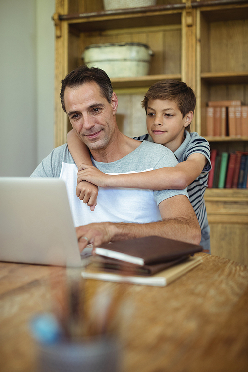 Father and son using laptop in study room at home