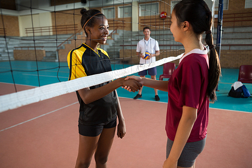 Two female players shaking hands with each other in the volleyball court