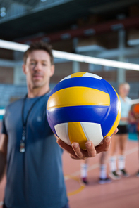 Close-up of coach holding volleyball in the court