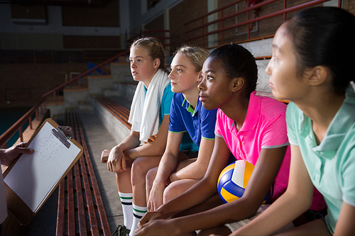 Mid-section of volleyball coach talking to female players