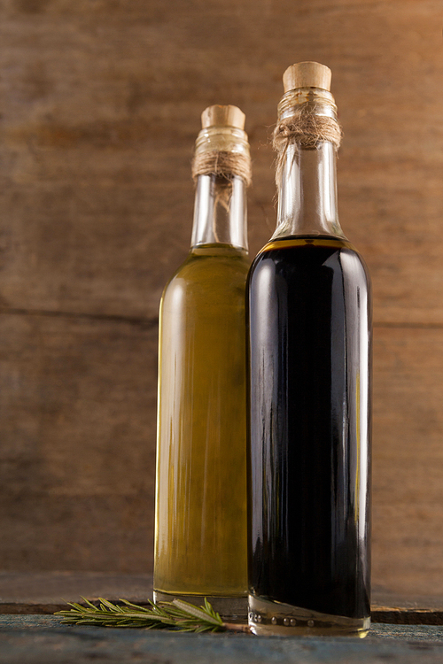 Close up of olive oil in bottles with herb on wooden table