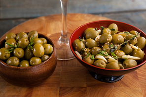Close up of green olives served in container on wooden table
