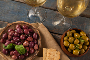 Directly above shot of black and green olives served by white wine on table