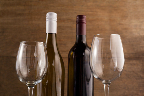 Close up bottles with wineglasses against wooden wall