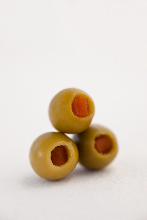 Close up of green olives arranged on white table